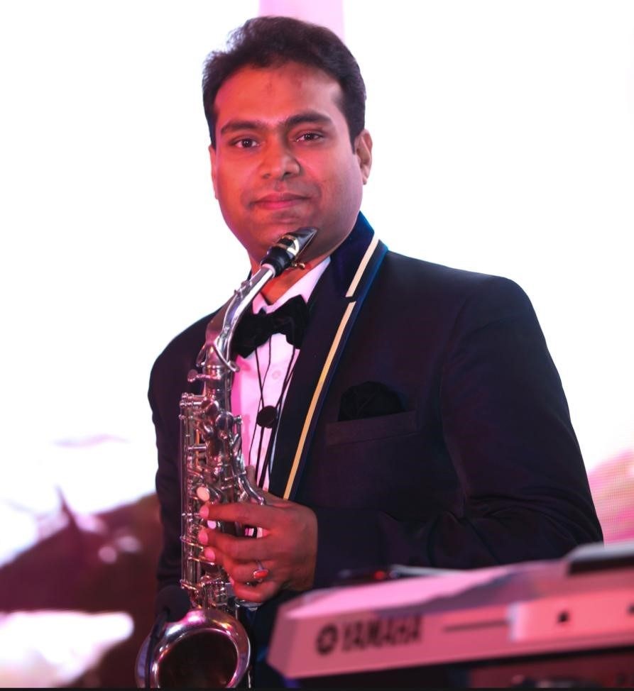 Vikas Gautam in a tuxedo with his alto saxophone at a formal evening event
