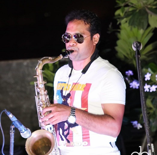 Vikas Gautam playing tenor saxophone live at an outdoor evening event